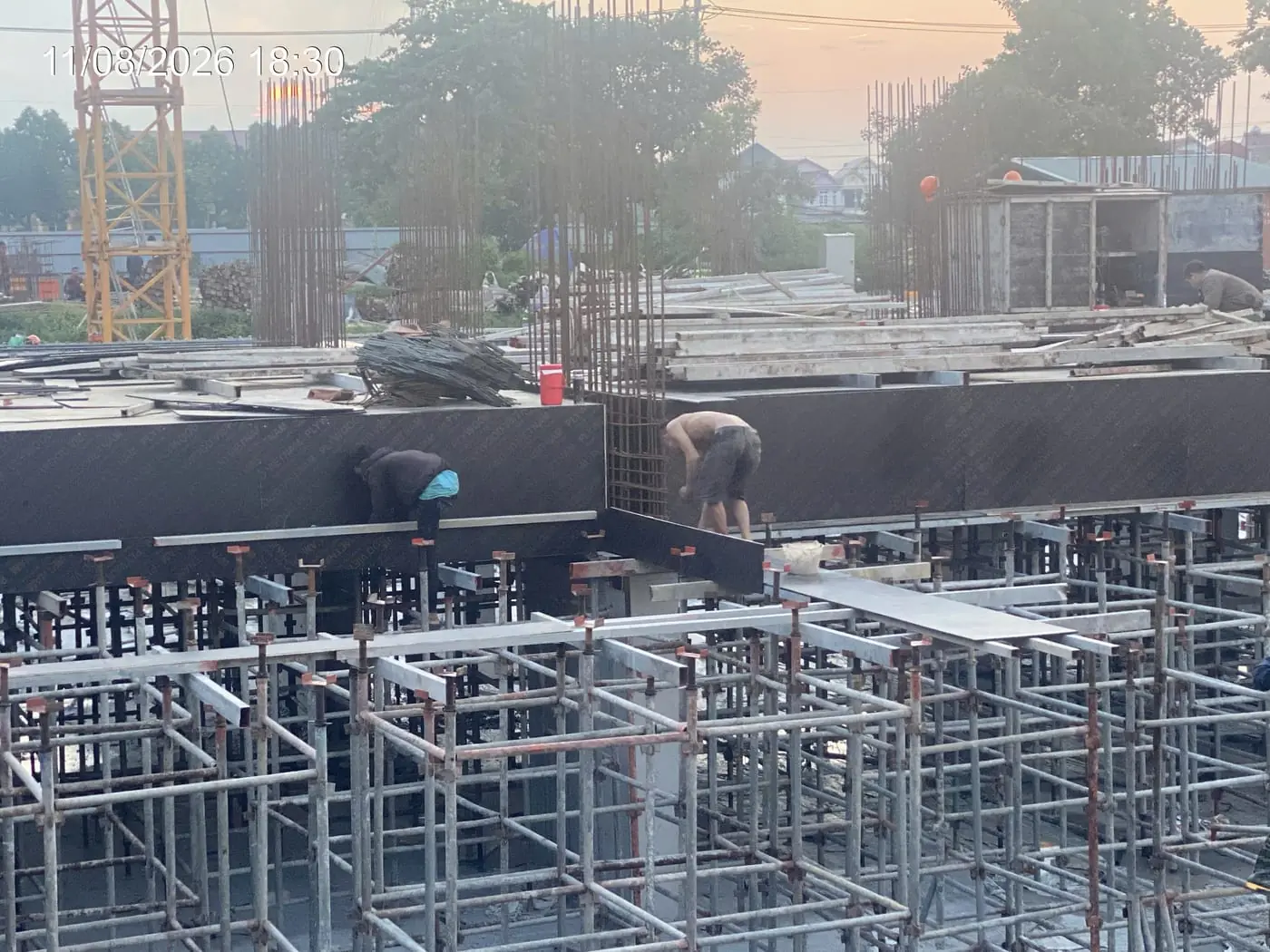 Công nhân thi công cốt thép cột lúc hoàng hôn, công trường NOXH Minh Đức ngày 11/08/2026